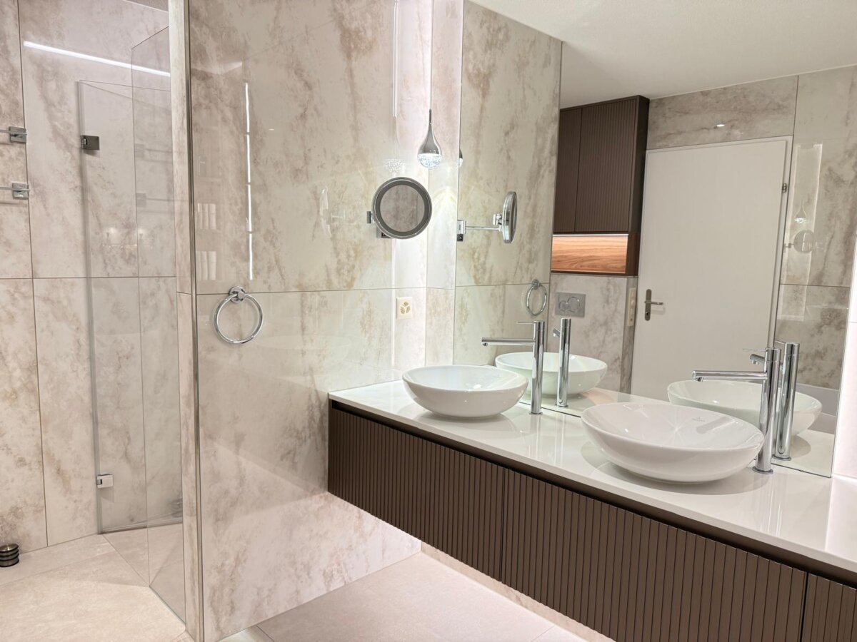 Badezimmer in Zürich mit bodenebener Dusche hinter Glas und Doppelwaschtisch in Nussbaum
